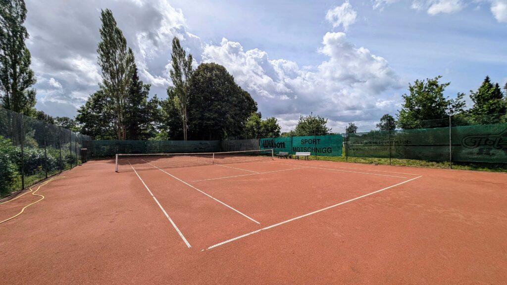 Bild des leeren Tennisplatzes der Tennisfreunde Ahrensfelde e.V., umgeben von Bäumen.