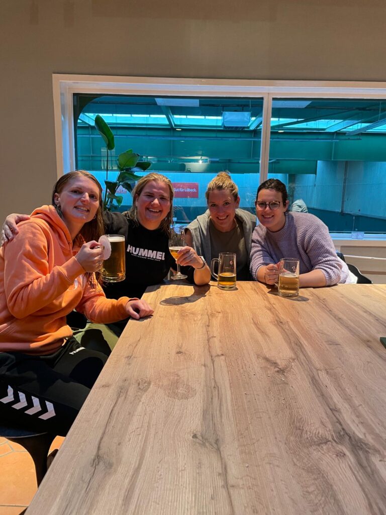 Vier Frauen, Mitglieder der Tennisfreunde Ahrensfelde e.V., sitzen an einem Tisch und halten jeweils ein Bier in der Hand.